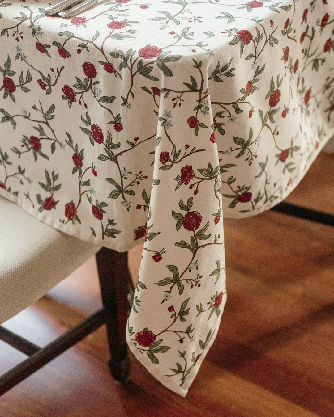 Traditional Christmas dining table set with red and green patterned linens, matching napkins, elegant place settings, and festive seasonal details.