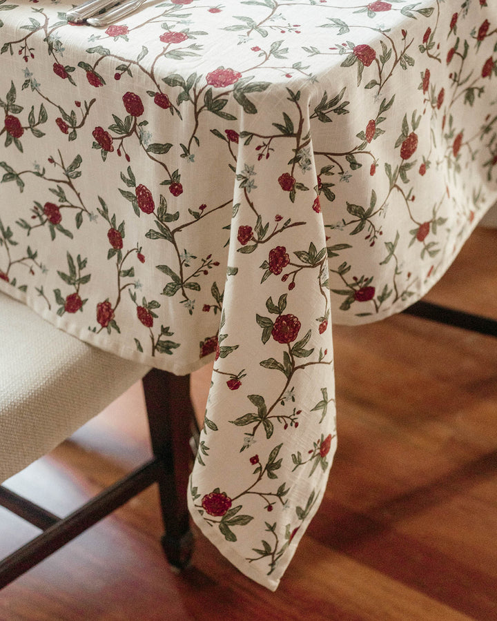 Traditional Christmas dining table set with red and green patterned linens, matching napkins, elegant place settings, and festive seasonal details.