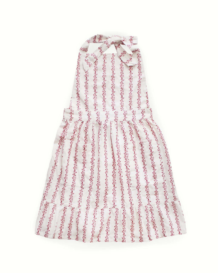 A red floral stripe smock apron dress featuring a vintage botanical and striped print with a playful ruffle hem. This 100% cotton baking apron for women includes two practical pockets and adjustable ties for a custom fit. Designed for grand millennial decor, it serves as a beautiful ruffle cooking apron or gardening apron. An ideal Mother's Day gift for mom and adult daughter to wear while hosting a spring brunch or preparing festive Easter baking meals together in a country kitchen.