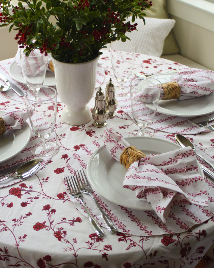 Elegant Christmas table set with red floral table linens, coordinating napkins, and classic holiday accents.