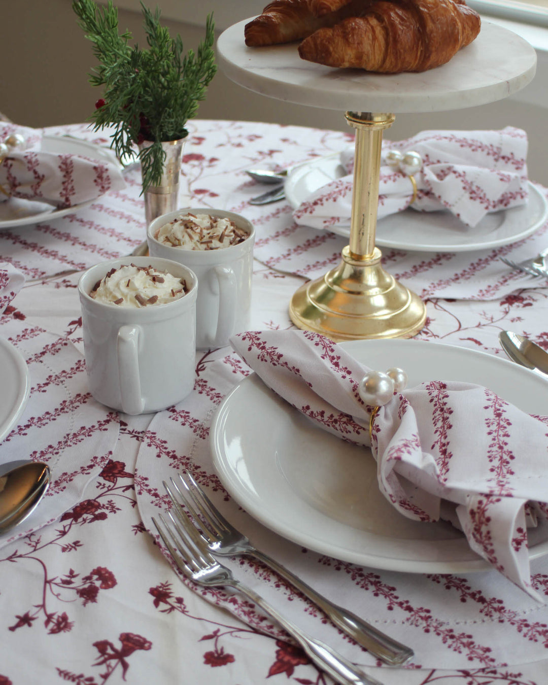 Red floral Christmas tablecloth and matching linens styled for an elegant holiday table setting.