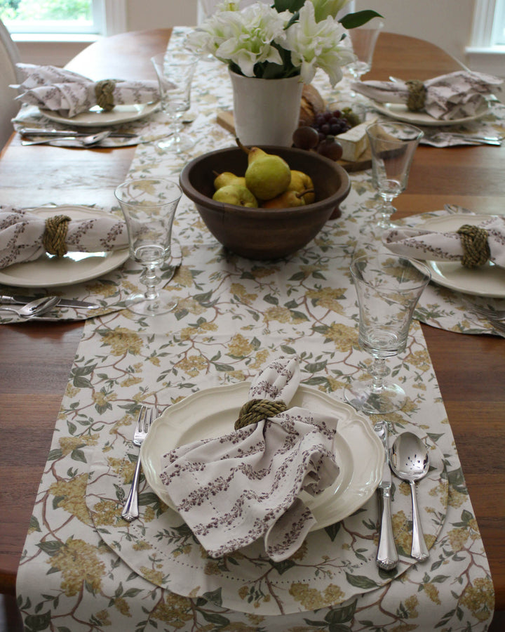 Beautiful spring-inspired floral table runner featuring hand-drawn yellow flowers and lush green leaves on a 100% cotton fabric. This elegant Easter table decor is available in 104-inch and 120-inch lengths to fit large dining tables. Perfect for holiday hosting, the botanical design adds a fresh, garden-party feel to your brunch. Crafted with non-toxic dyes, it’s a sustainable choice for your Easter linens and spring celebrations. Elevate your home with this organic cotton runner.